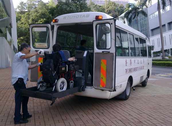 A wheelchair user is boarding a rehabus with the driver's help.
